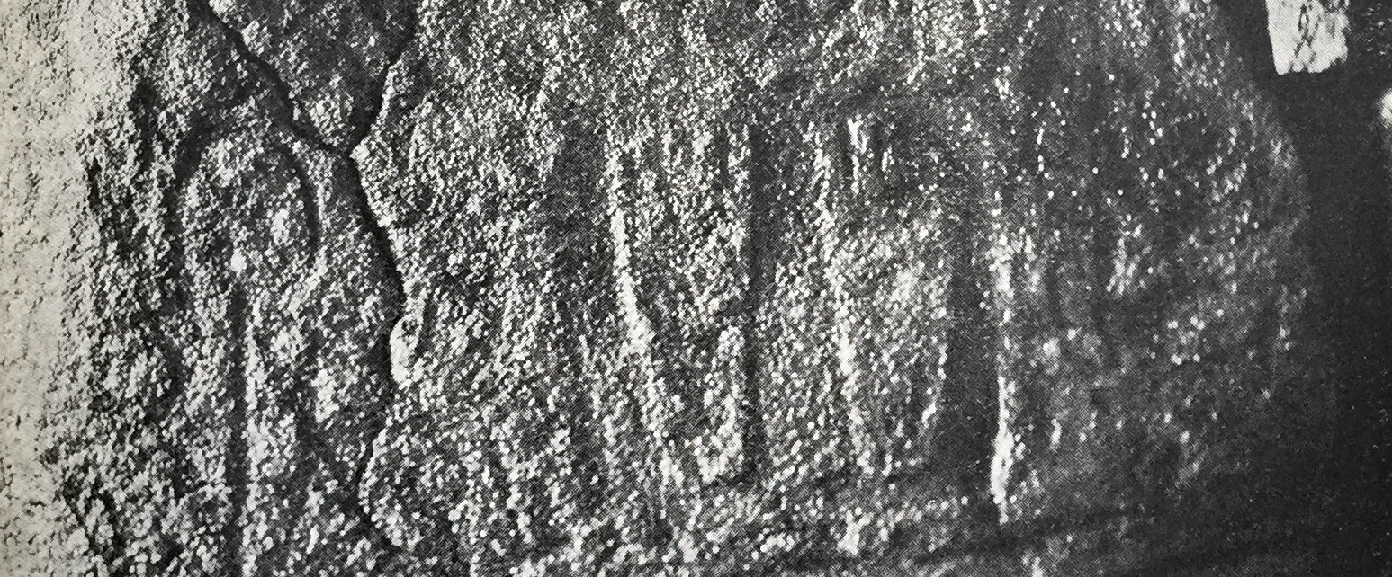 Black and white photo of a carved pair of feet, soles outwards, on a stone (now missing) from a passage grave in Brittany, France.