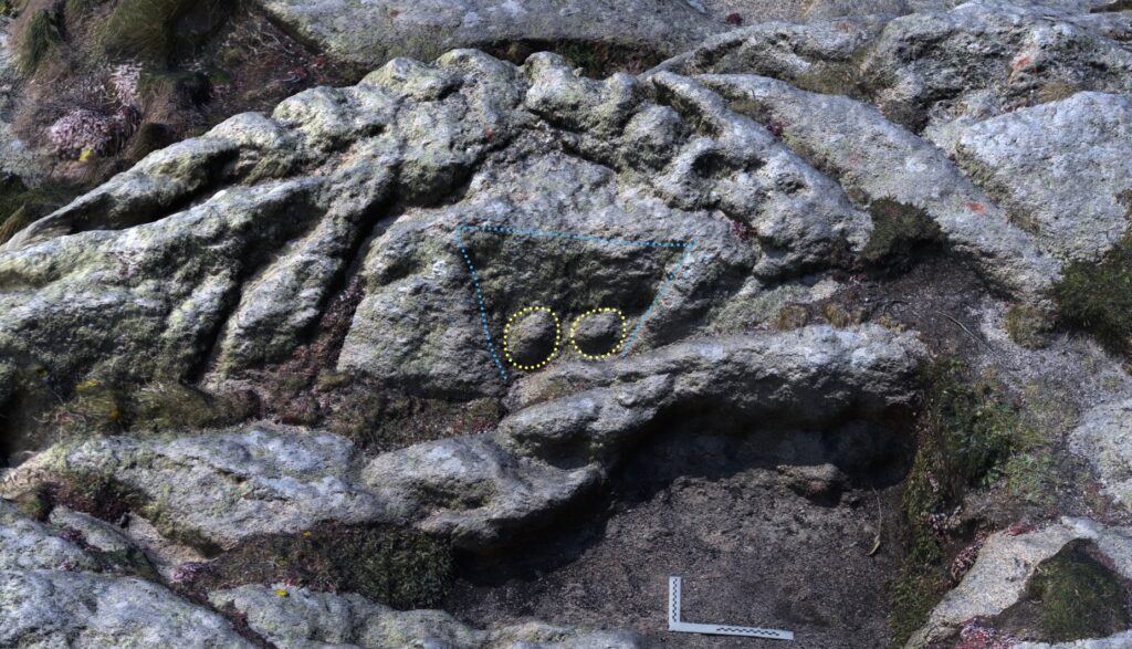 A computer generated image of the decorated stone at Carn Leskys. Ambient Occlusion shading has been used to increase the visibility of carved areas. A dotted blue line outlines the trapezoidal panel containing the two breast motifs, which are outlined with a dotted yellow line.